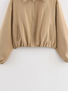 Detailed close-up of a khaki cropped jacket with front metal zipper and elastic hem design