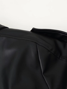 Detailopname van zwart kunstleren jack met dubbele stiksels en gladde textuur