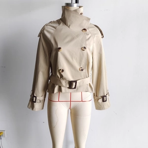 Detail of beige short double-breasted trench jacket with waist belt and epaulets