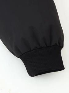 Close-up of black windproof ribbed cuffs and premium textured fabric on the cropped jacket