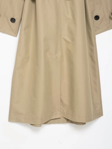 Detailed close-up of khaki trench coat fabric featuring black button sleeve cuff straps