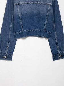 Detail of blue washed denim jacket showing hem and cuffs with metal buttons