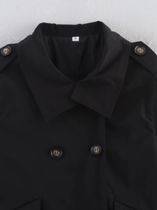 Close-up of lapel and shoulder strap details on a luxury black minimalist trench coat