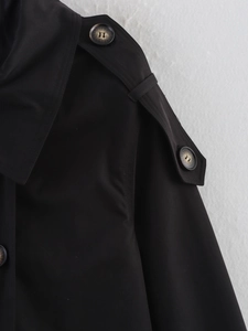Detailed view of shoulder epaulets and marble buttons on the black trench coat