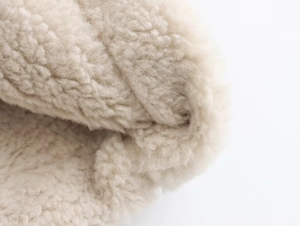 Dettaglio macro della spessa fibra di pile sherpa bianco crema morbida e riccia