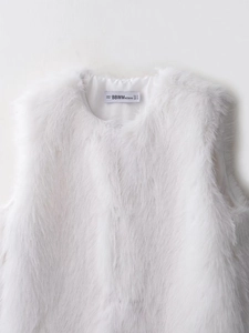Detailed view of white faux fur vest showing soft long-hair texture and inner lining label