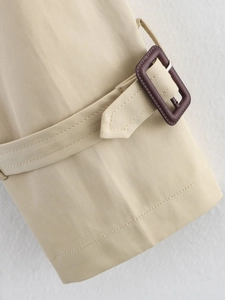 Detail of khaki trench coat sleeve cuff with adjustable strap and resin square buckle