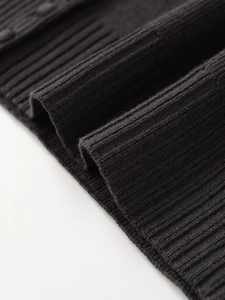 Close-up of high-quality black ribbed knit fabric texture on a woman's cardigan