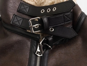Dettaglio del collo in shearling con doppi cinturini in pelle e cerniera in metallo argento