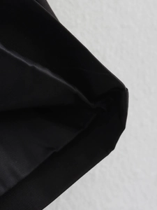 Close-up detail of high-quality black twill fabric stitching on a minimalist trench coat
