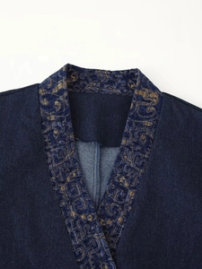 Detail of dark blue denim kimono collar with ornate gold and blue floral embroidery