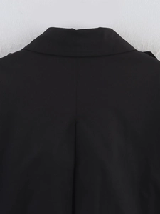 Detailed close-up of the black trench coat lapel and back pleat design with fine stitching