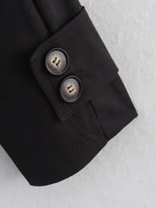 Detail of minimalist black trench coat cuff with tortoiseshell texture buttons