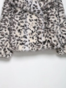 Macro texture of soft faux fur snow leopard print on a warm winter jacket fabric