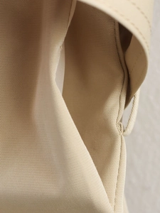 Detailed macro view of beige twill fabric texture and reinforced stitching on short trench coat