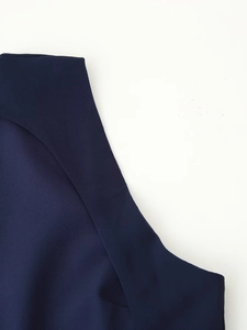 Detailed close-up of dark blue dress stitching and fabric texture on a white background