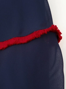 Macro detail of dark blue chiffon fabric featuring a contrast red fringe trim and texture