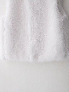 Close-up of fluffy white faux fur vest texture showing soft dense fibers and premium lining