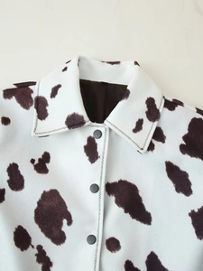 Detailansicht von Tierprint-Jackenkragen mit schwarzen Knöpfen und braunem Kuhmuster