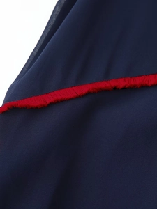 Detail of navy blue chiffon fabric with vibrant red fringe trim and soft textured finish