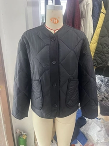 Detail of black quilted jacket featuring round neckline and front utility pockets