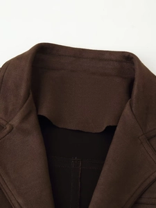 Detail view of the notch lapel and fine stitching on the dark brown suede-like jacket