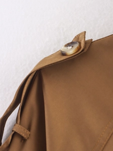 Detailed macro view of camel trench coat shoulder epaulette with a tortoise shell button