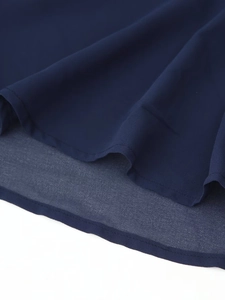 Detail of navy blue contrast dress showing layered hem and fine stitching texture