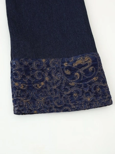 Detail of navy blue jacquard cuff with golden baroque floral patterns on denim jacket