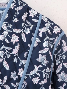 Close-up of diamond-quilted floral pattern with contrast piping on a navy jacket
