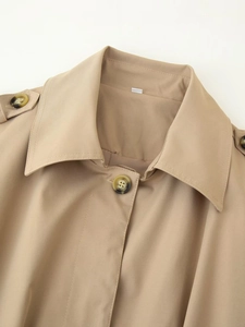 Detail of khaki trench coat collar featuring epaulettes and tortoise shell buttons