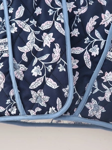 Close-up of quilted floral jacket with navy fabric, pink flowers and blue piping