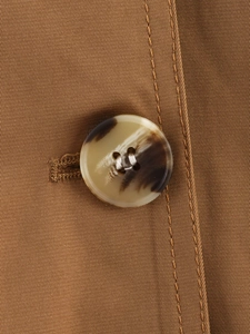 Detail of the tortoiseshell button and premium brown twill fabric on this cropped trench coat