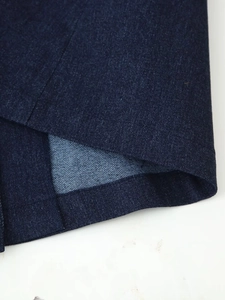 Detailed close-up of dark blue denim hem with professional double stitching and fabric texture