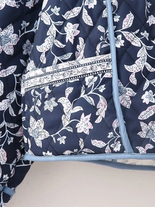 Detail of floral quilted jacket featuring blue satin piping and refined stitch work