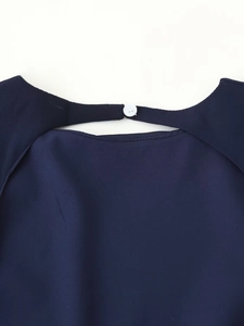 Macro shot of back neckline teardrop cutout with button closure on navy dress