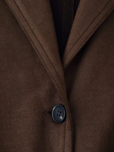 Detail of faux suede jacket featuring notched lapels and branded black button closure