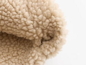 Dettaglio macro del tessuto in pile beige per giacche invernali da donna