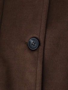Close-up of a premium black engraved button on a dark brown suede-effect jacket
