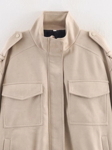 Detail view of beige faux suede jacket with stand collar, shoulder straps and flap pockets