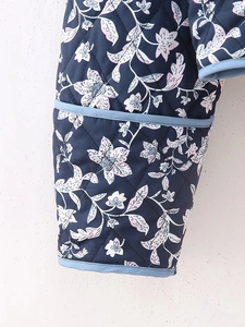 Close-up of quilted floral jacket sleeve with vintage navy print and light blue trim