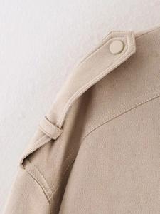 Close-up of beige suede jacket shoulder epaulette with matte button and fine stitching