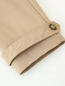 Detailed close-up of khaki trench coat cuff with tortoiseshell button and fine stitching