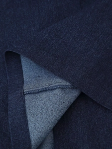 Close-up of deep blue denim fabric with twill texture and neat rolled hem stitching