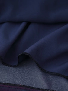 Detailed macro view of dark blue layered fabric with precise edge stitching and texture