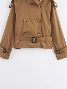 Detailed macro view of cropped trench coat featuring buckle waist and shoulder epaulettes