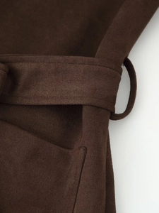Detail of a dark brown faux suede jacket featuring a matching waist belt and stitching