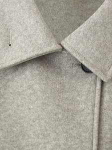Detailed macro view of beige wool coat lapel with premium stitching and black button
