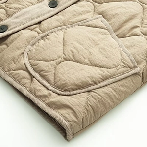 Detail of khaki quilted jacket featuring gourd pattern stitching and large patch pocket