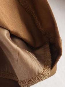 Detail view of khaki trench coat inner lining showing precise stitching and satin texture